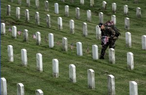 Sgt. Timothy Davis of San Diego places American flags before the gravestones of those buried at Arlington Cemetery.